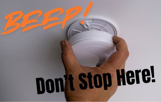 Hand removing smoke detector on ceiling.